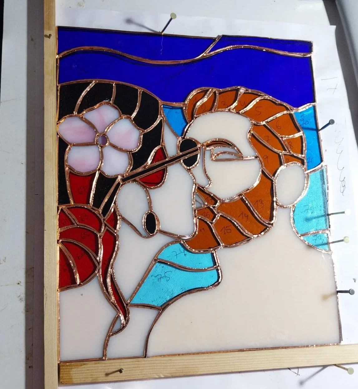 Vitral Tiffany El Beso estilo Klimt en proceso con foil de cobre sobre la mesa de trabajo